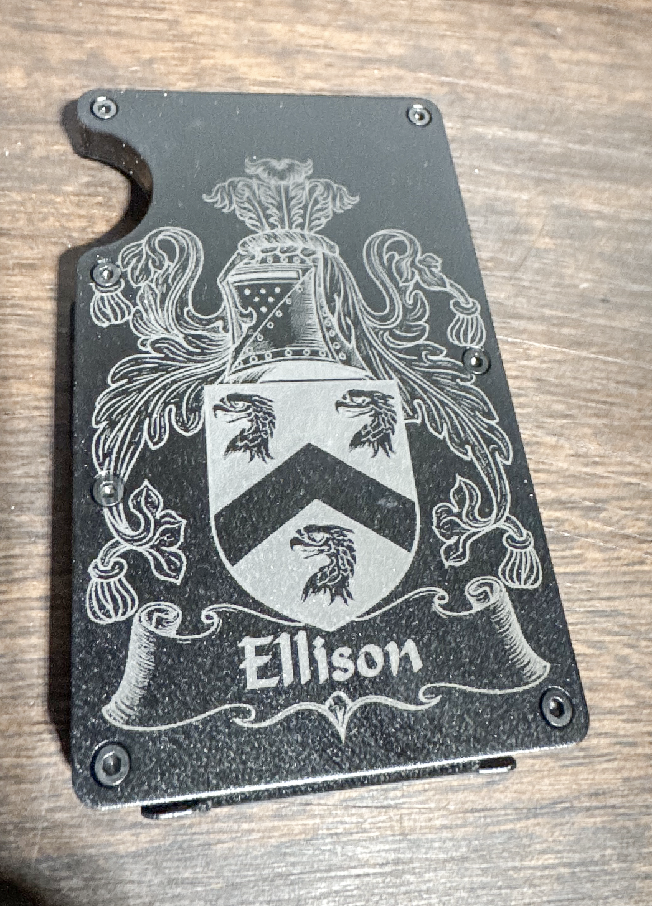 Black metal wallet engraved with a detailed family crest